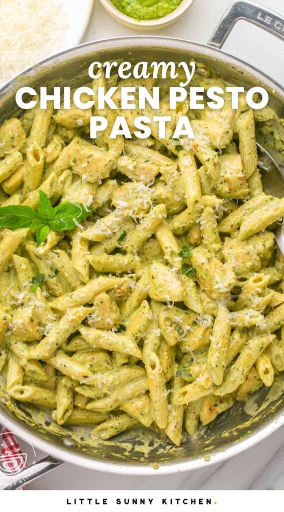 A two handled skillet filled with creamy pesto penne with chicken. A sprig of basil is added for garnish.