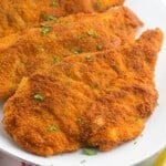 Breaded and fried chicken schnitzel cutlets served on a white platter