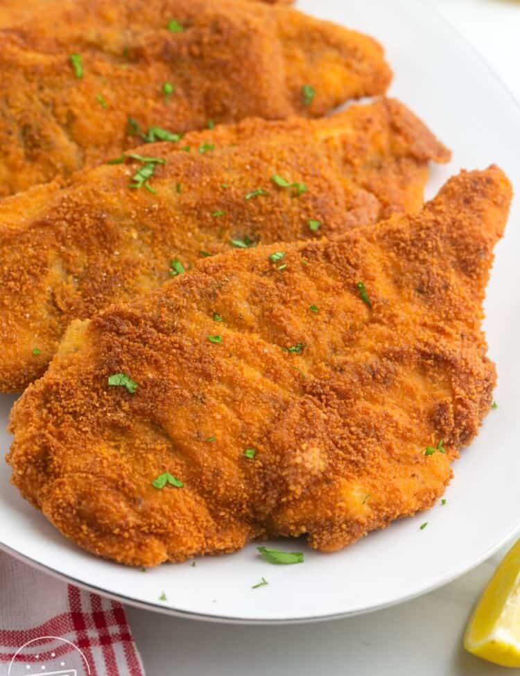 Breaded and fried chicken schnitzel cutlets served on a white platter