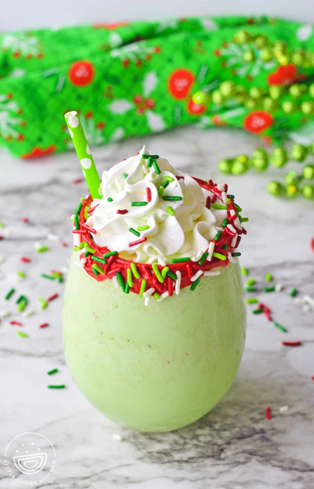 Christmas milkshake with rimmed glass and sprinkles, topped with whipped cream and extra sprinkles
