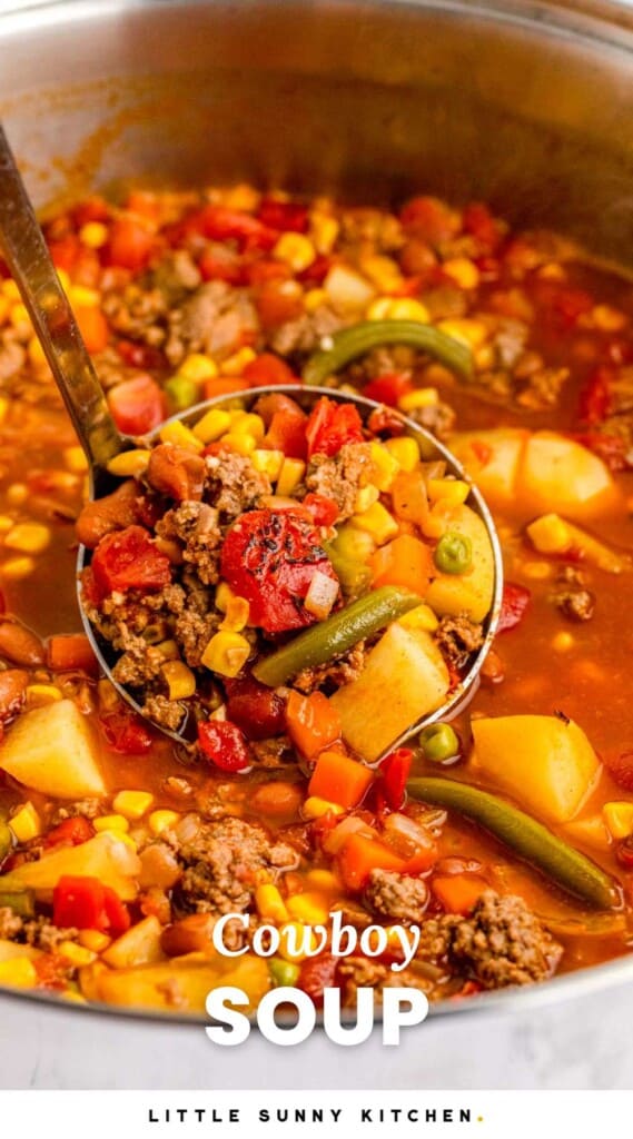 closeup view of a metal pot of cowboy soup with fire roasted tomatoes and corn. A ladle is lifting up a serving to show the detail. Text at bottom of image says "cowboy soup"