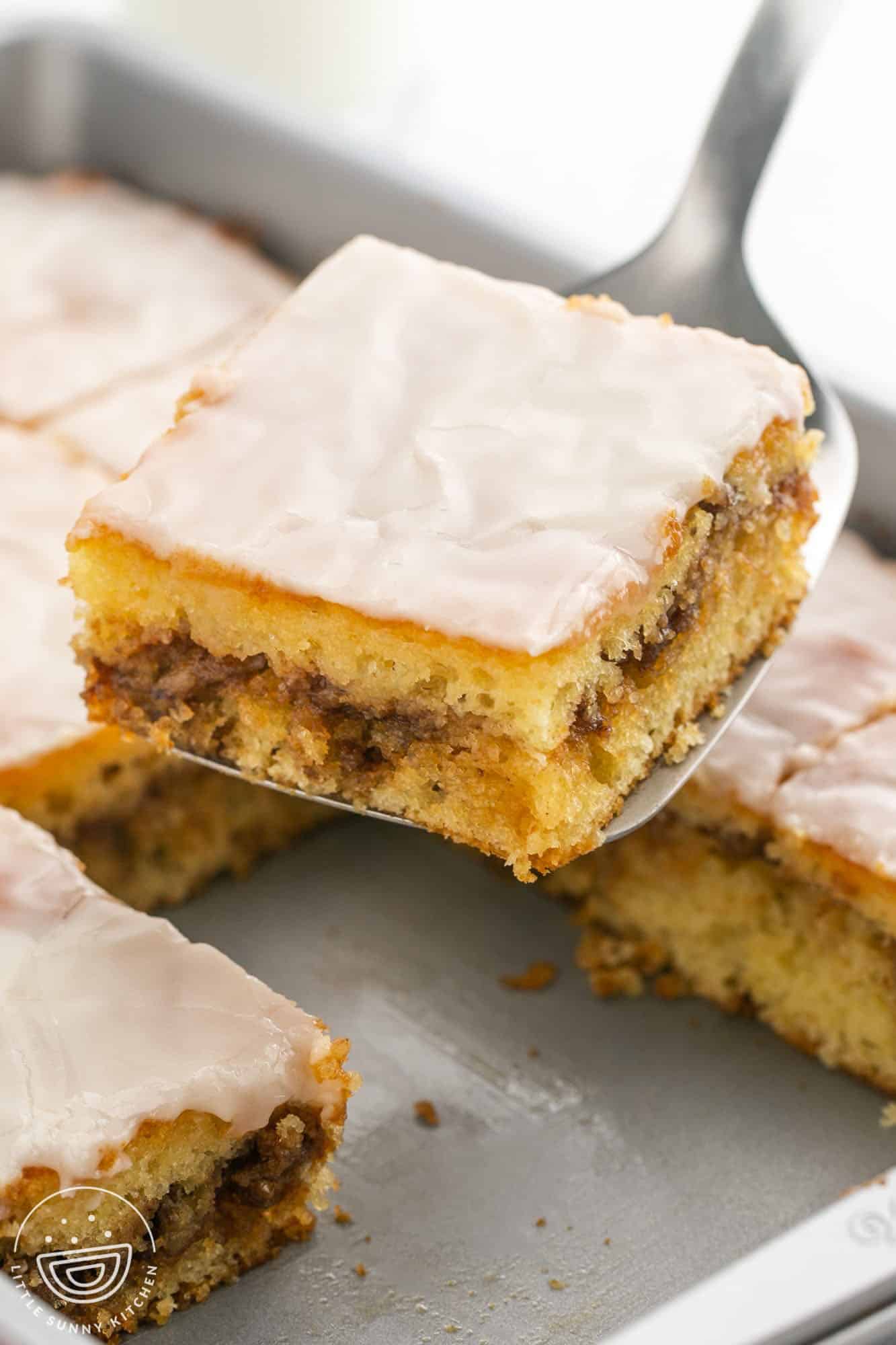 a slice of honey bun cake being lifted from the pan.