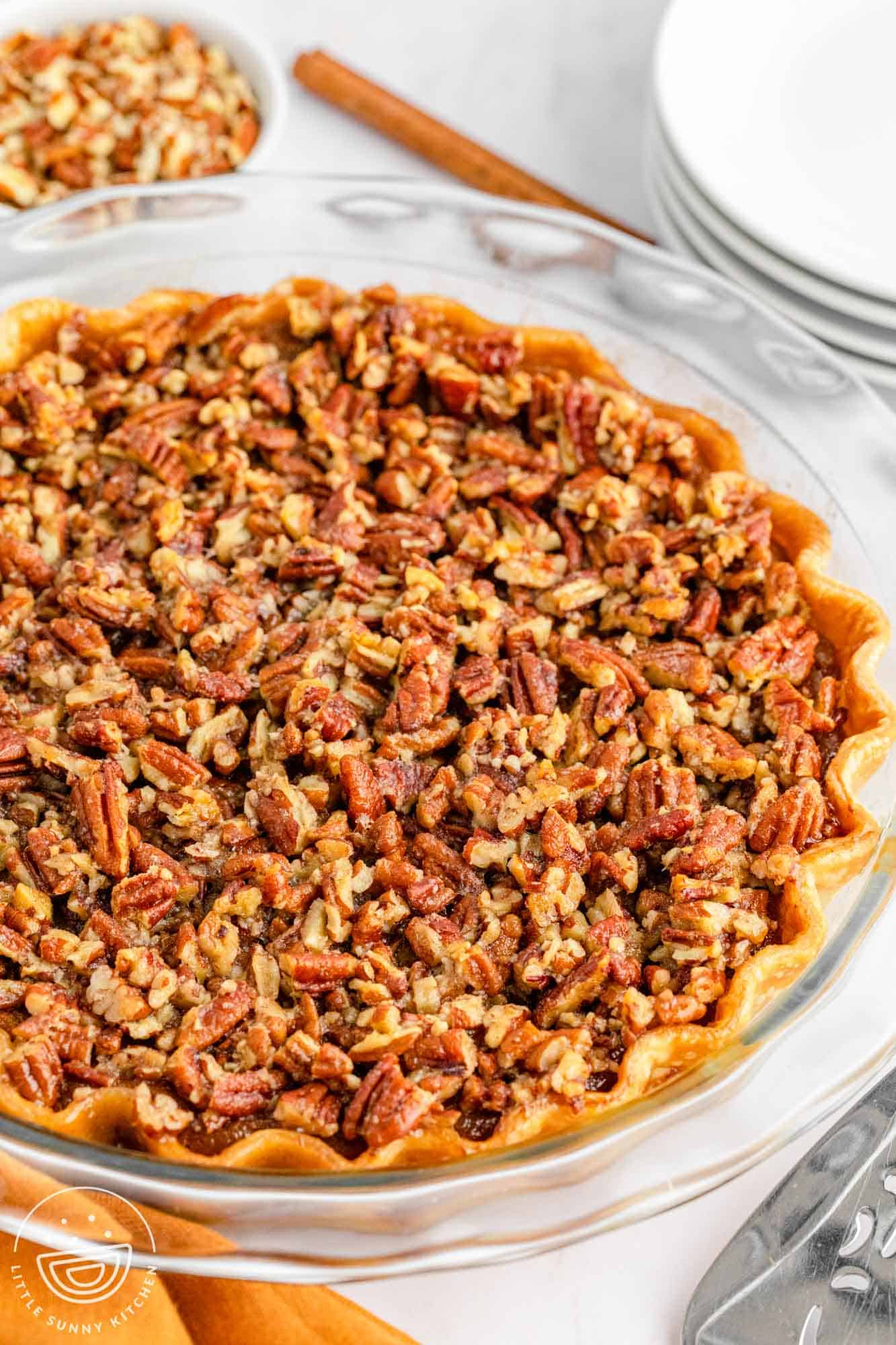 A whole pie in a glass pie dish, topped with pecans.