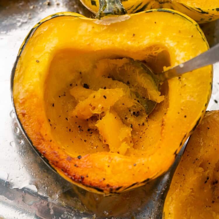 Roasted acorn squash halves, and a spoon to show the cooked flesh