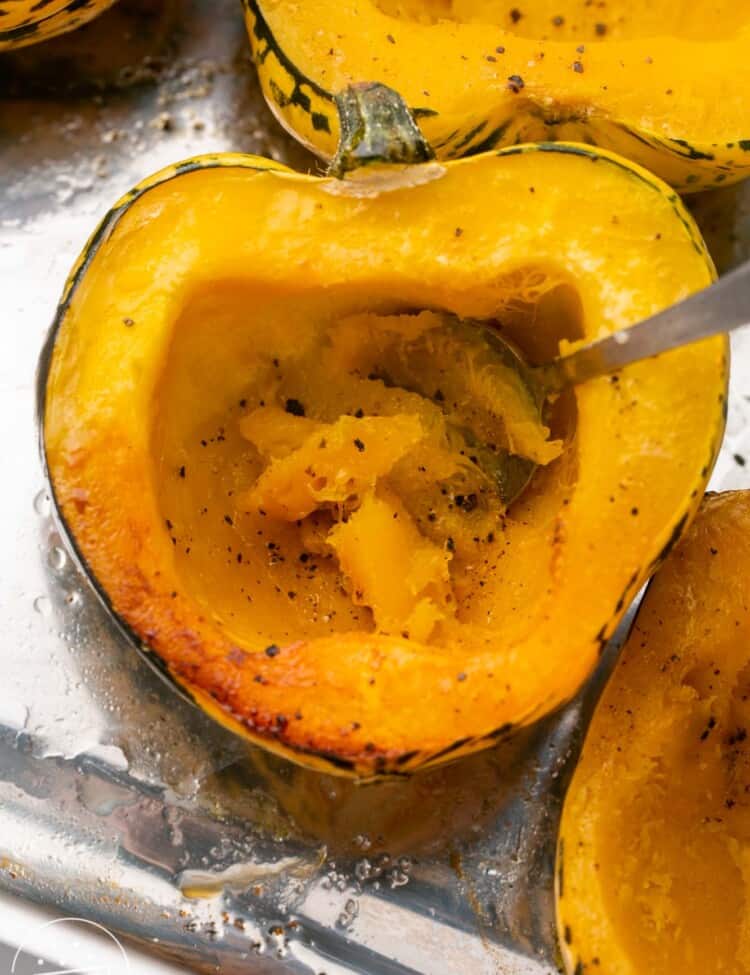 Roasted acorn squash halves, and a spoon to show the cooked flesh