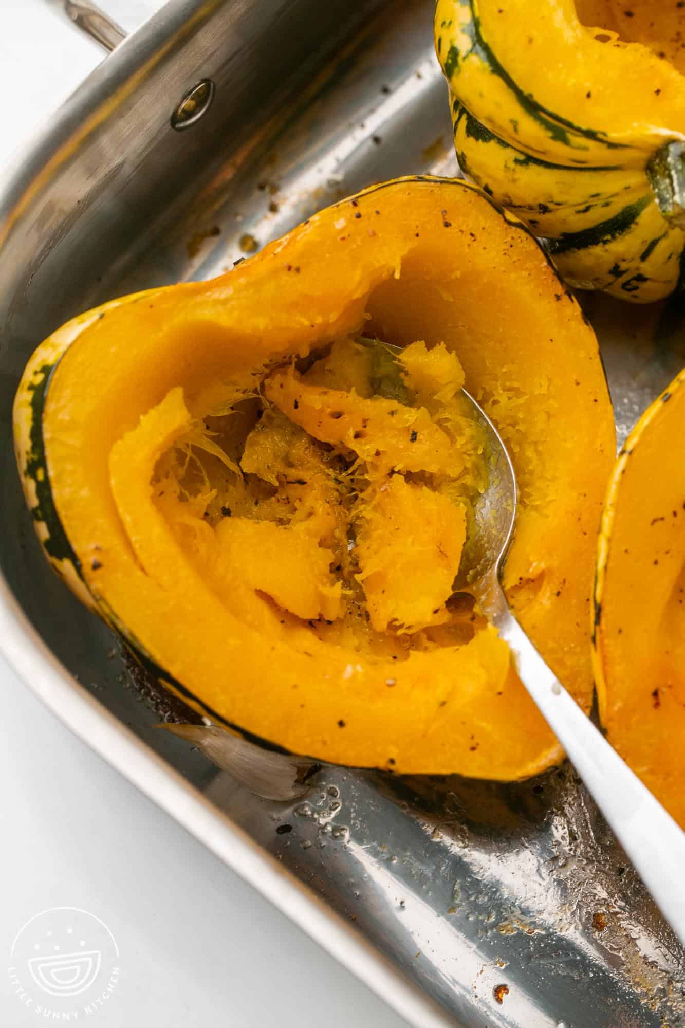 Scooping out the flesh or a roasted acorn squash with a spoon