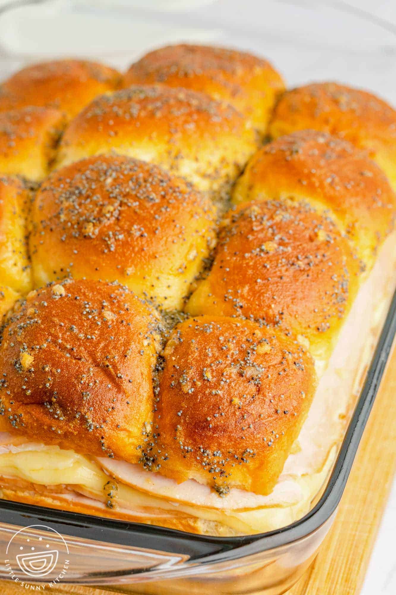 a glass baking dish with hawaiian roll sliders baked in it.
