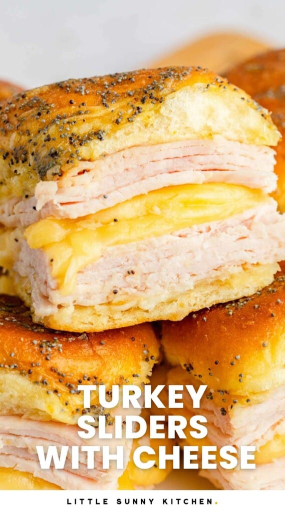turkey and cheese sliders stacked on top of each other. There are two layers of turkey with melty cheese in between.