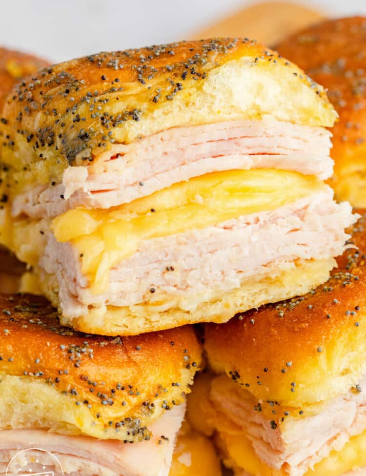 Turkey and cheese sliders stacked on top of each other. There are two layers of turkey with melty cheese in between.