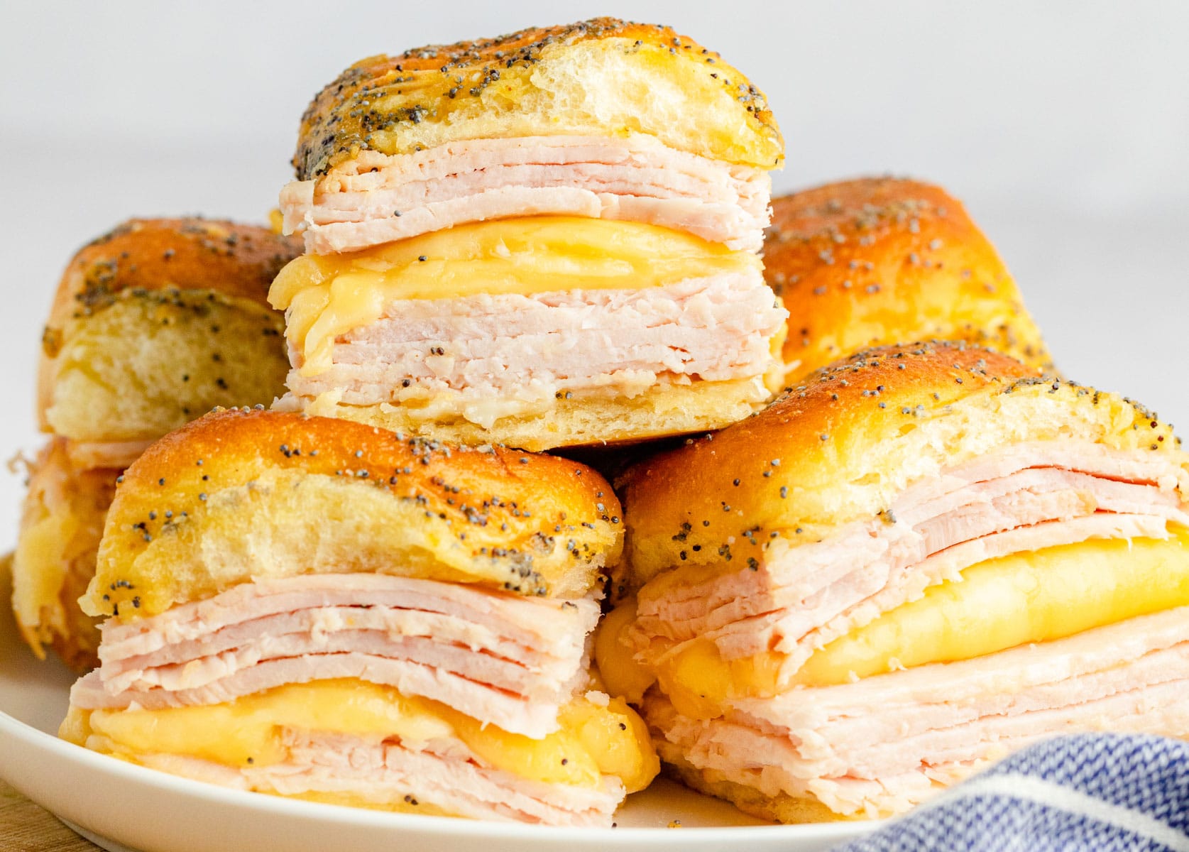 Turkey and cheese sliders on Hawaiian rolls with a poppy seed topping.