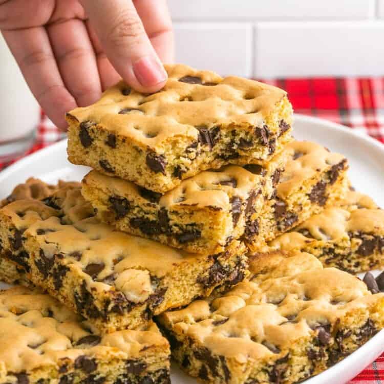 Taking a chocolate chip cookie bar from a plate