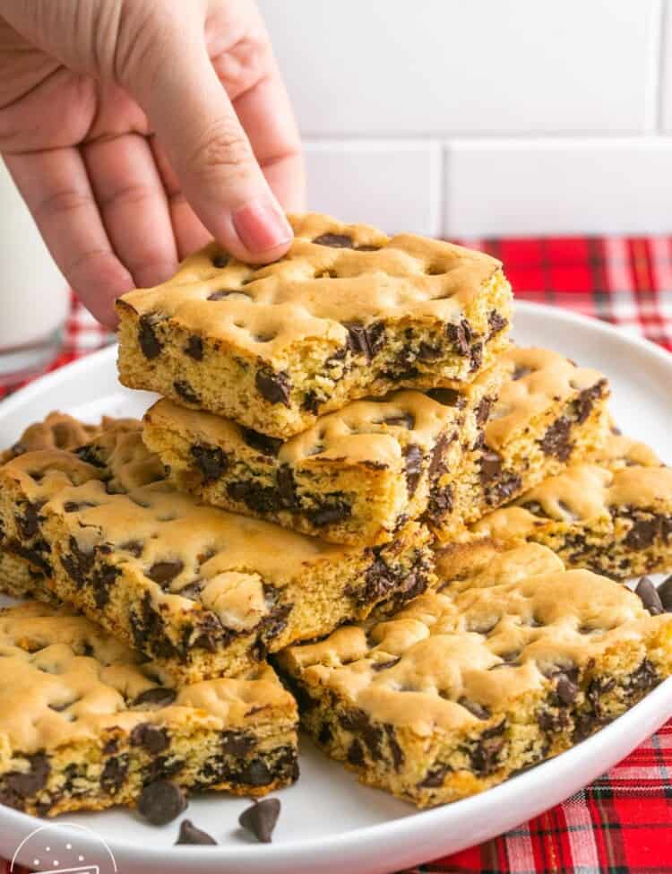 Taking a chocolate chip cookie bar from a plate
