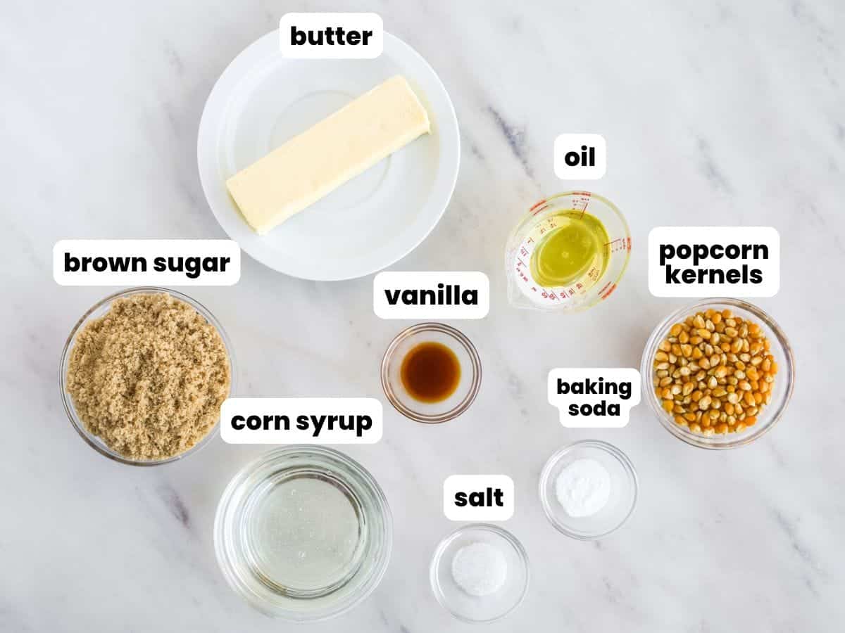 The ingredients for making homemade caramel popcorn, in separate bowls on a marble counter.