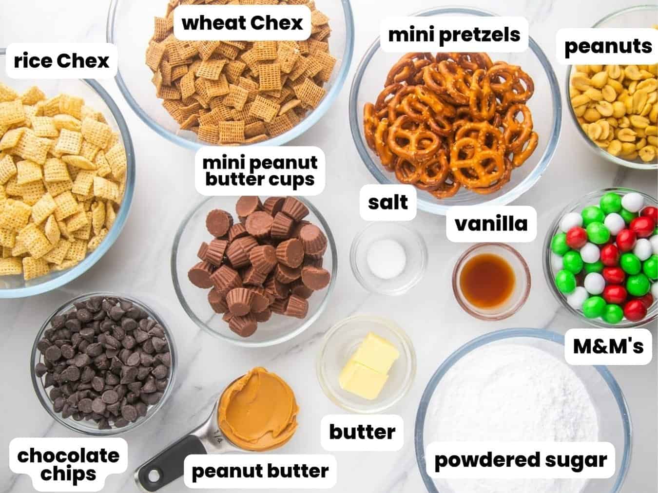 All of the ingredients needed to make christmas puppy chow, in separate bowls on the counter.