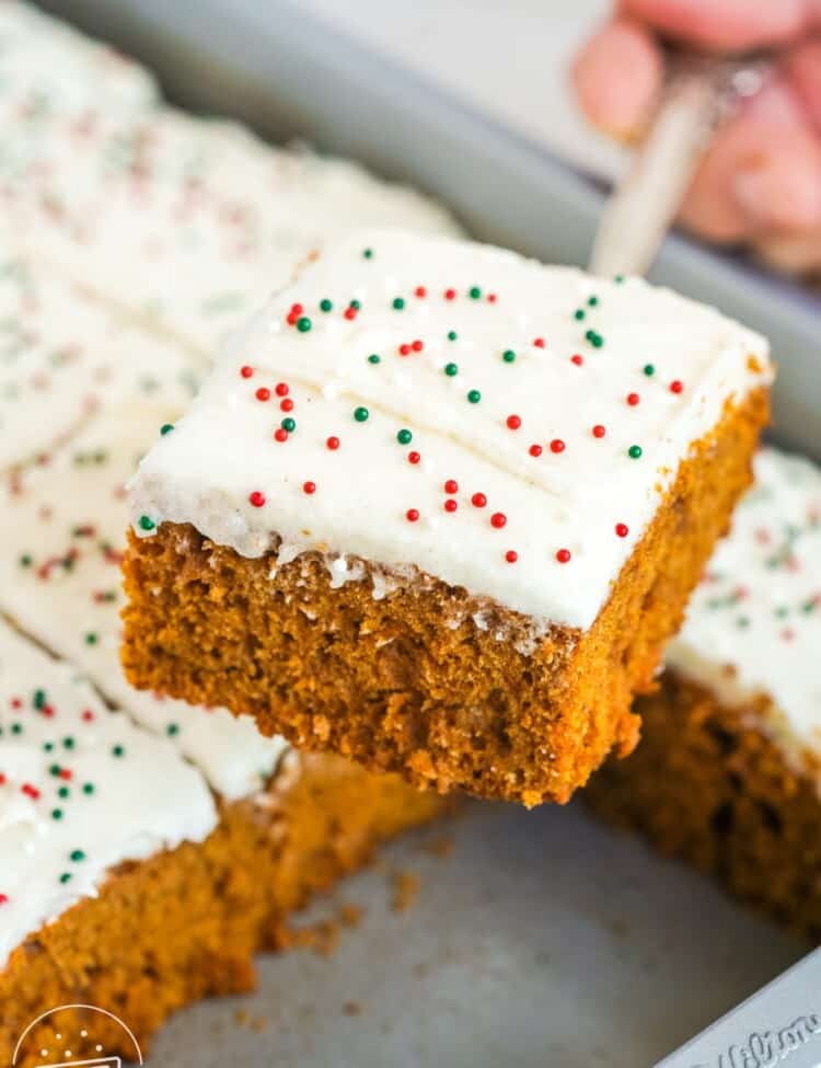 a spatula holding up a square of frosted gingerbread cake over the pan.