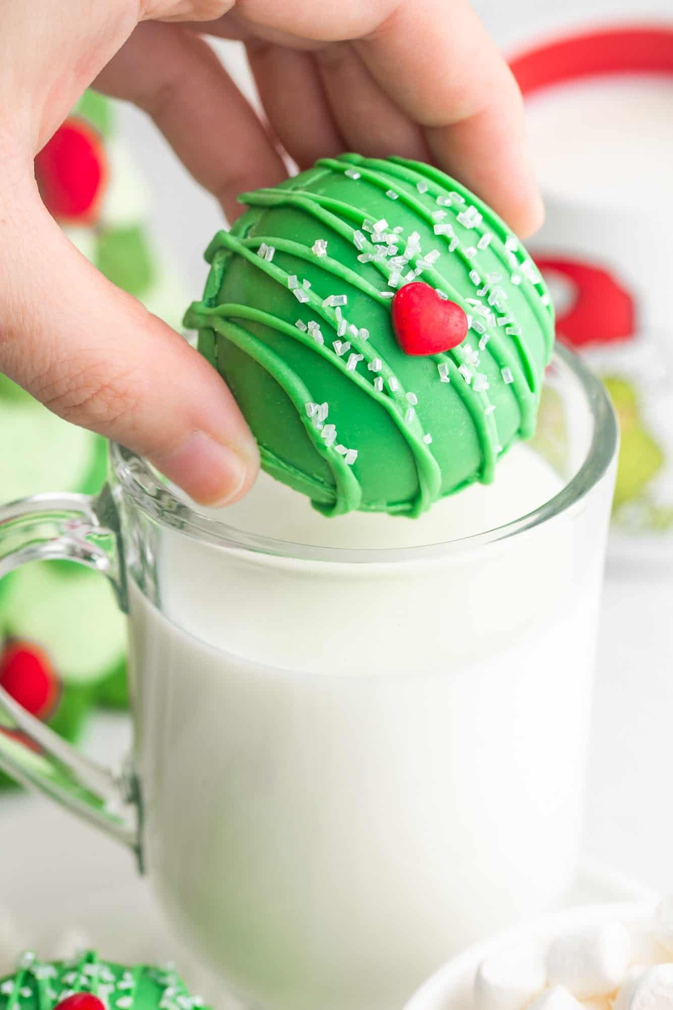 Adding a green hot chocolate bomb to a cup with hot milk