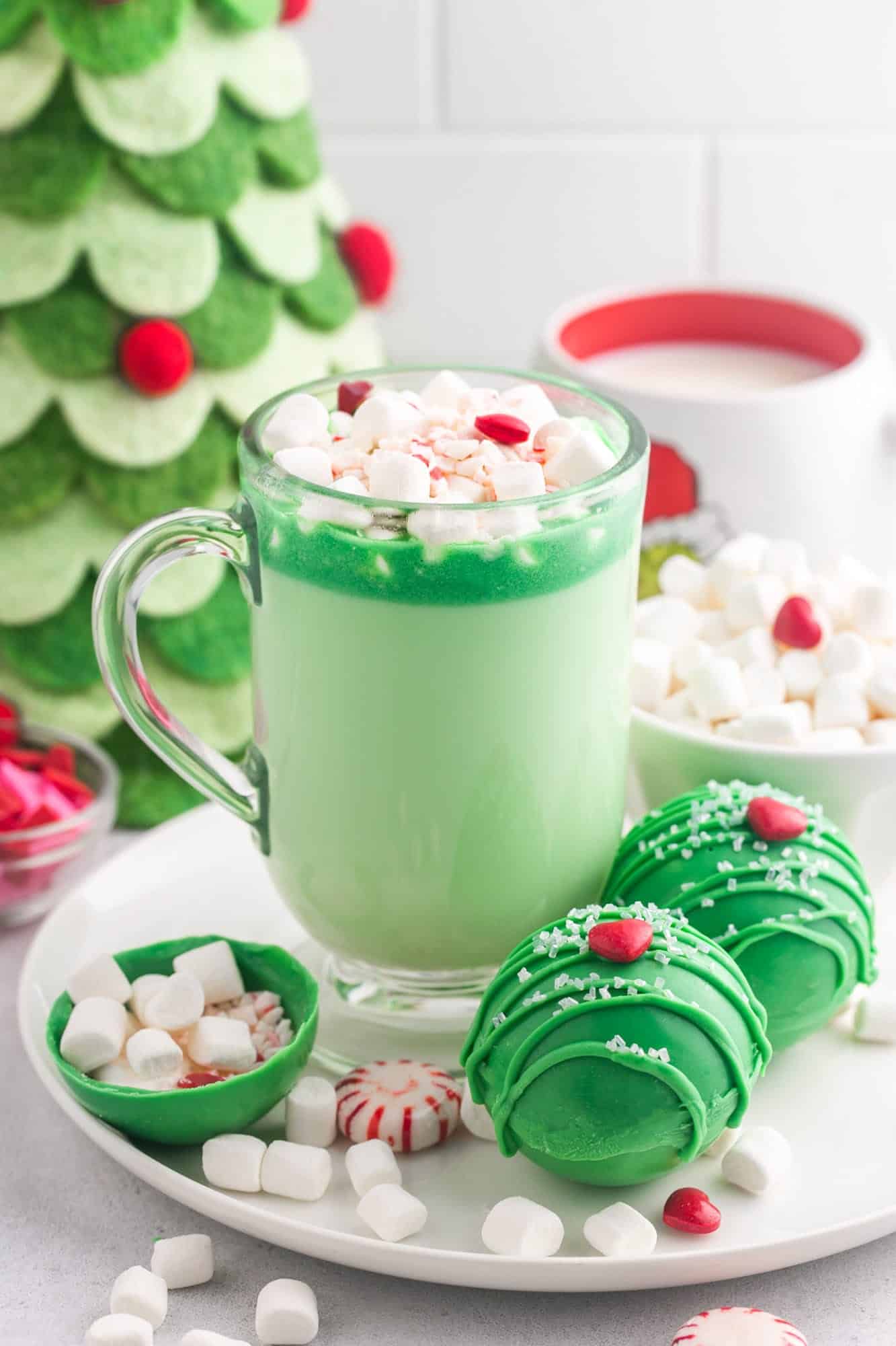 A glass with green hot chocolate and grinch hot chocolate bombs