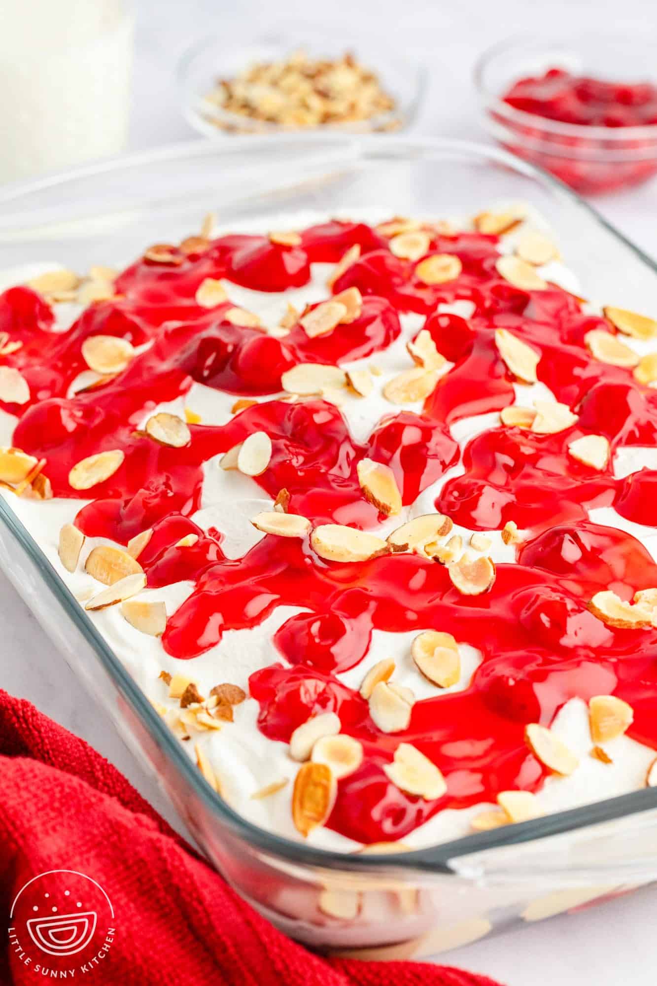 Heavenly cake in a glass pyrex pan, topped with cool whip, cherries, and almonds.