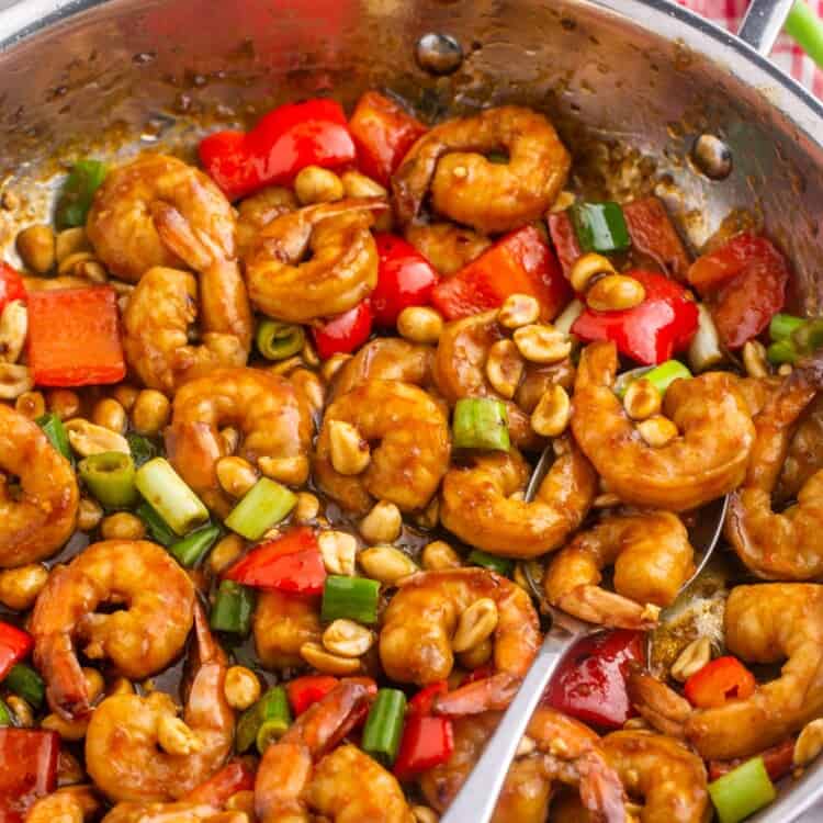 Kung pao shrimp in a skillet with a serving spoon