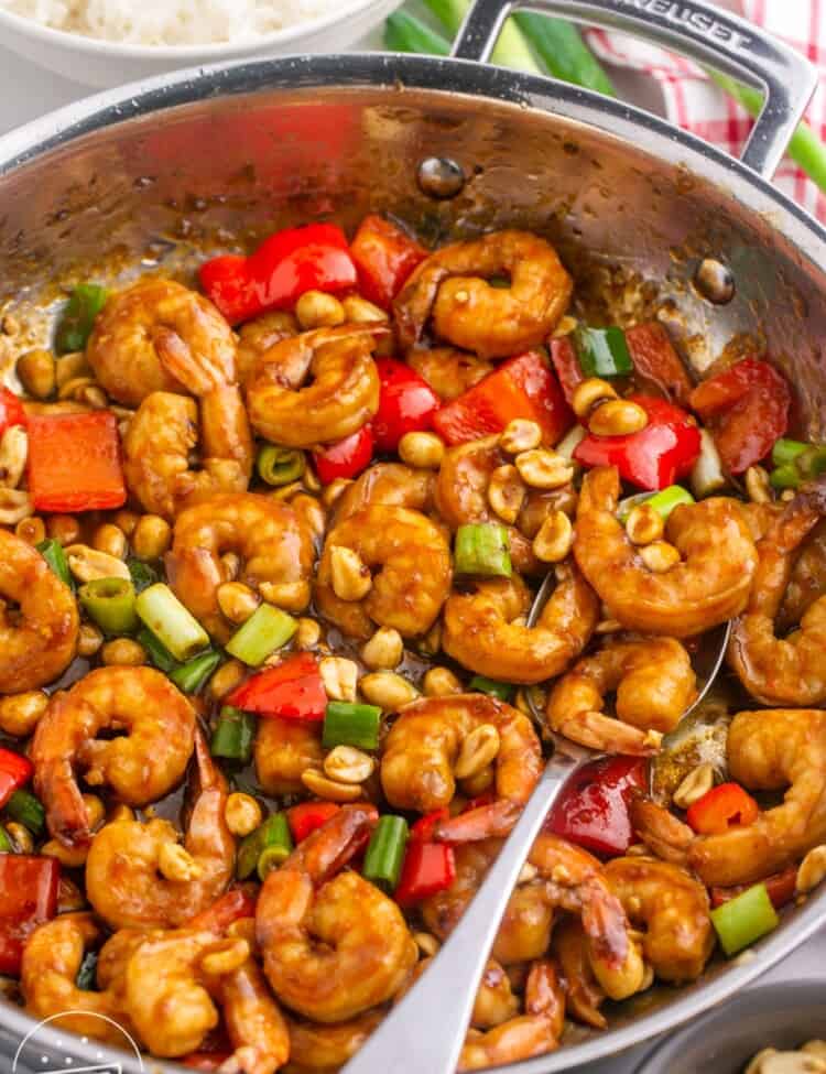 Kung pao shrimp in a skillet with a serving spoon