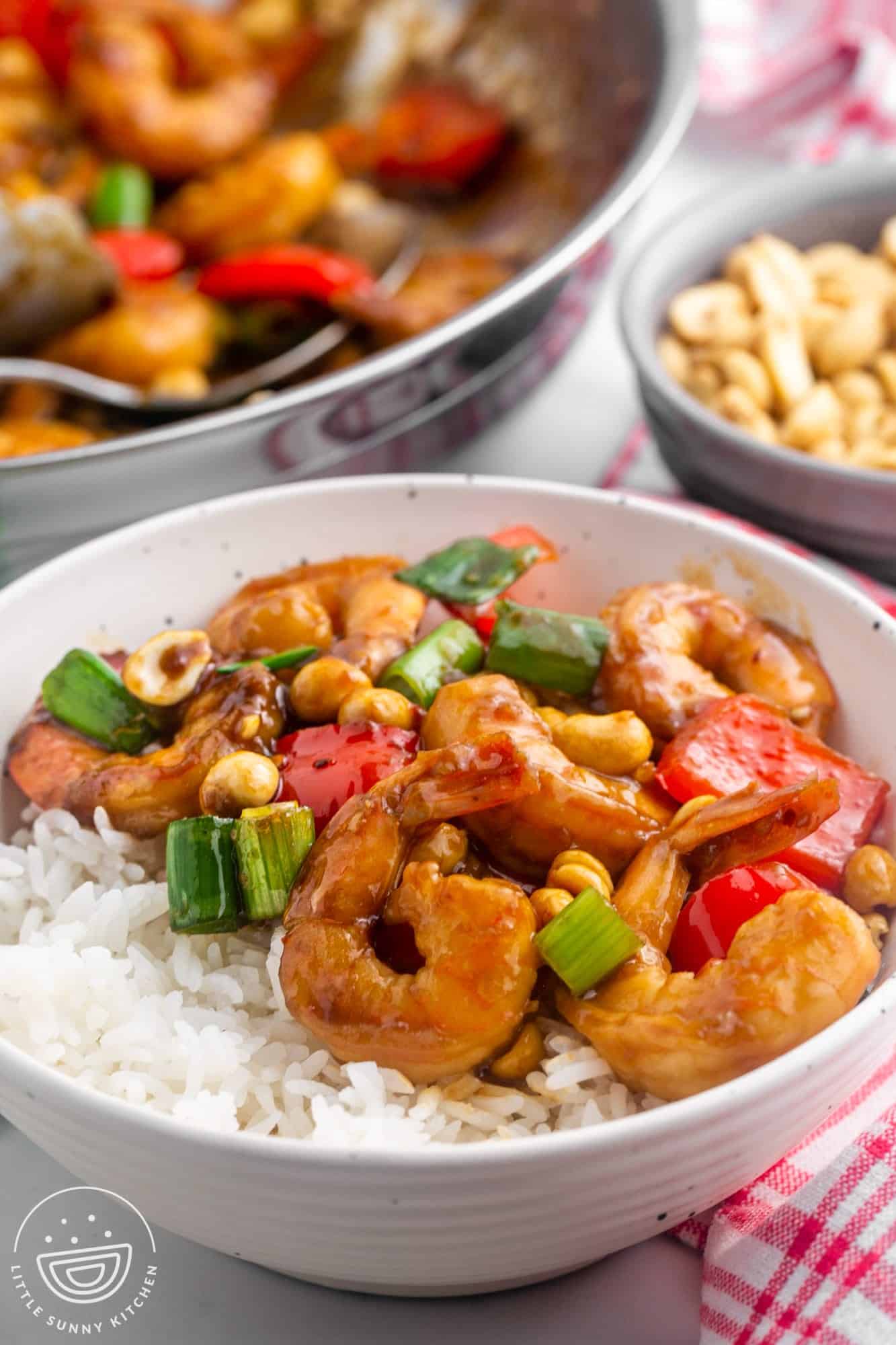 Kung pao shrimp served over white rice in a white bowl