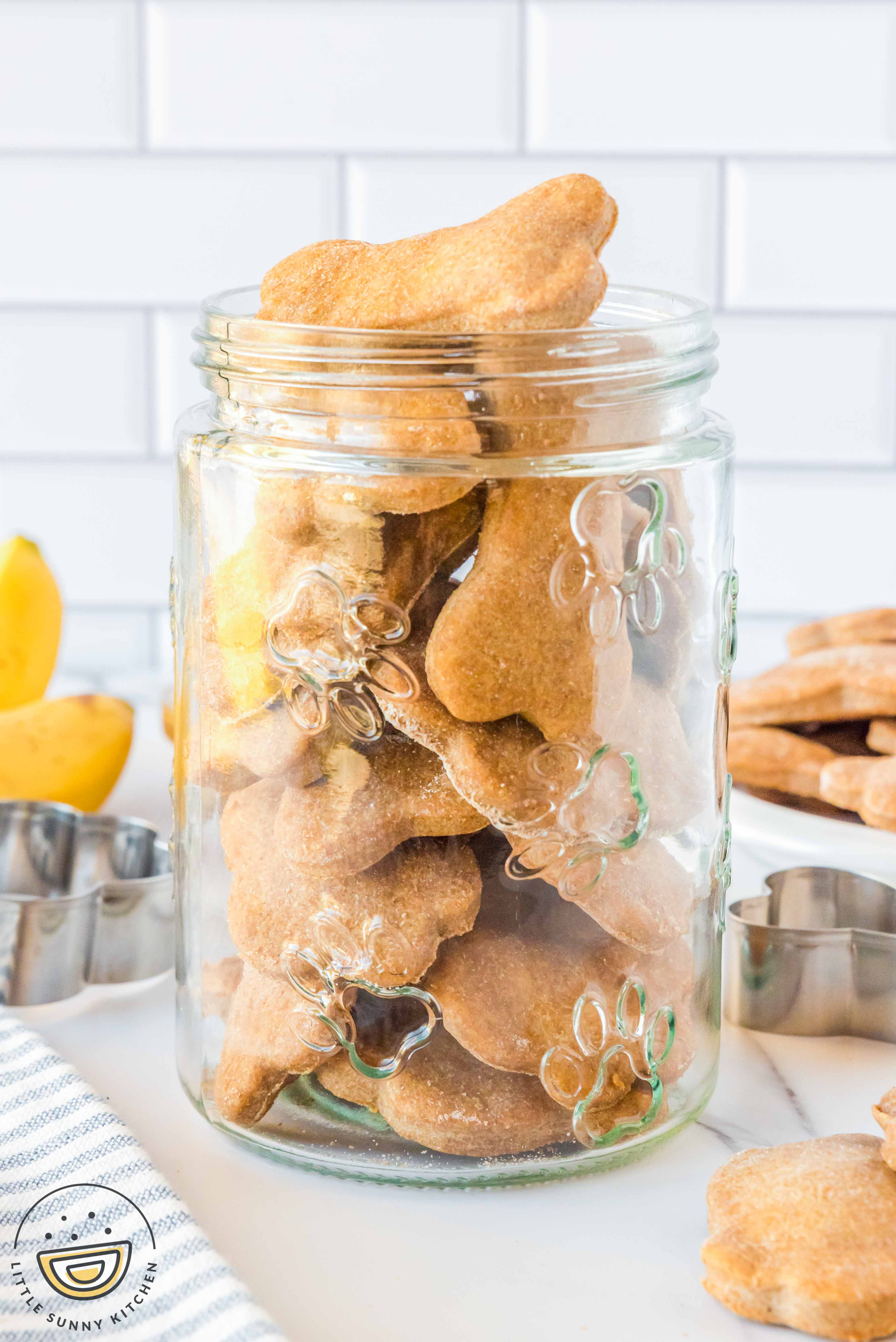 A clear canister filled with homemade peanut butter banana dog treats.