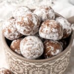 a gray bowl filled with powdered sugar covered rum balls.
