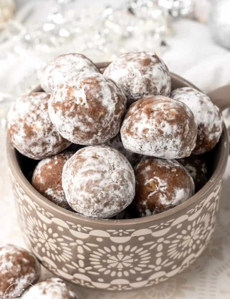 a gray bowl filled with powdered sugar covered rum balls.