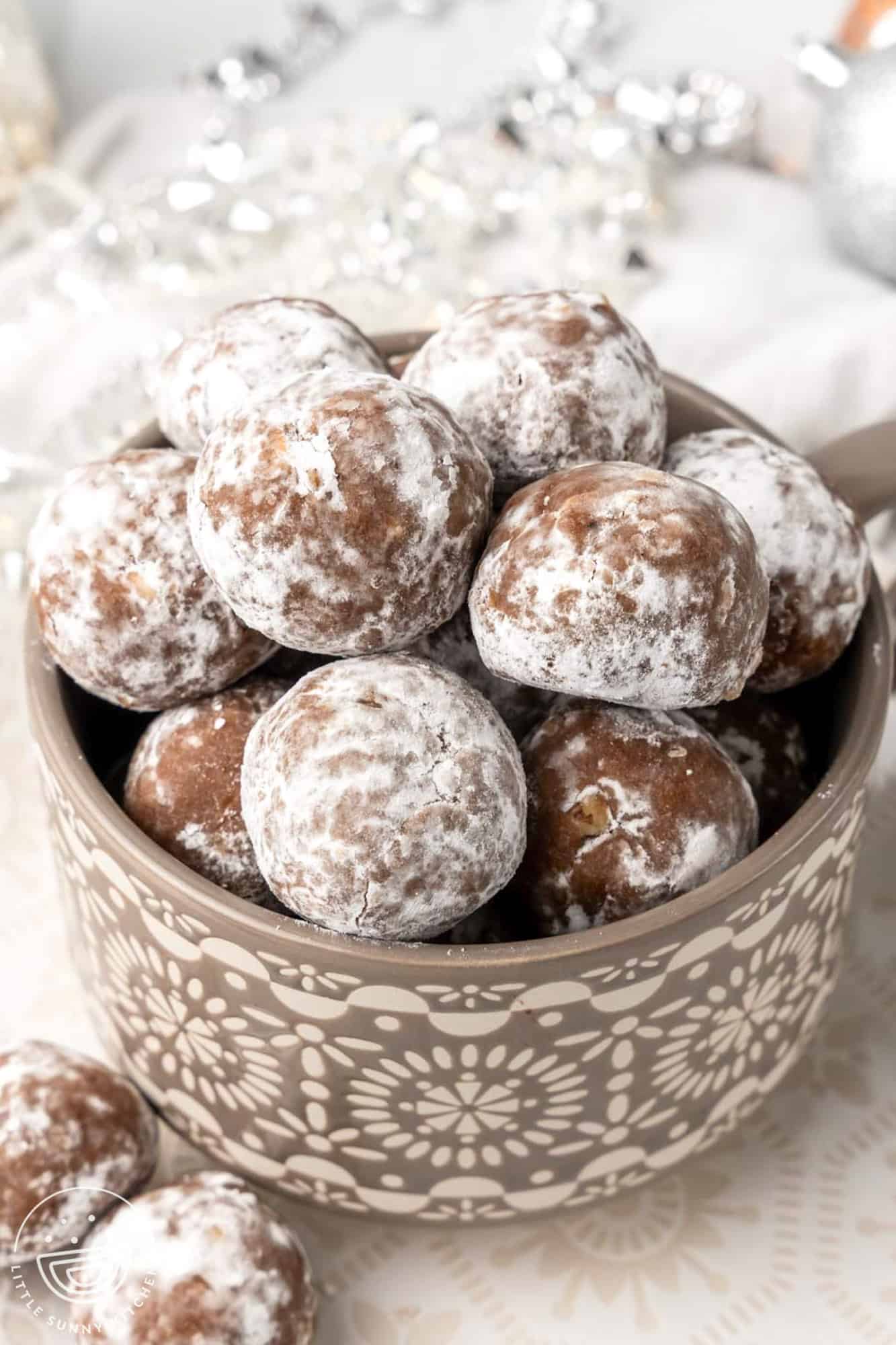 a gray bowl filled with powdered sugar covered rum balls. 