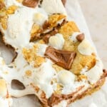 s'mores cookie bars cut on a piece of parchment paper. The marshmallow cream is gooey.