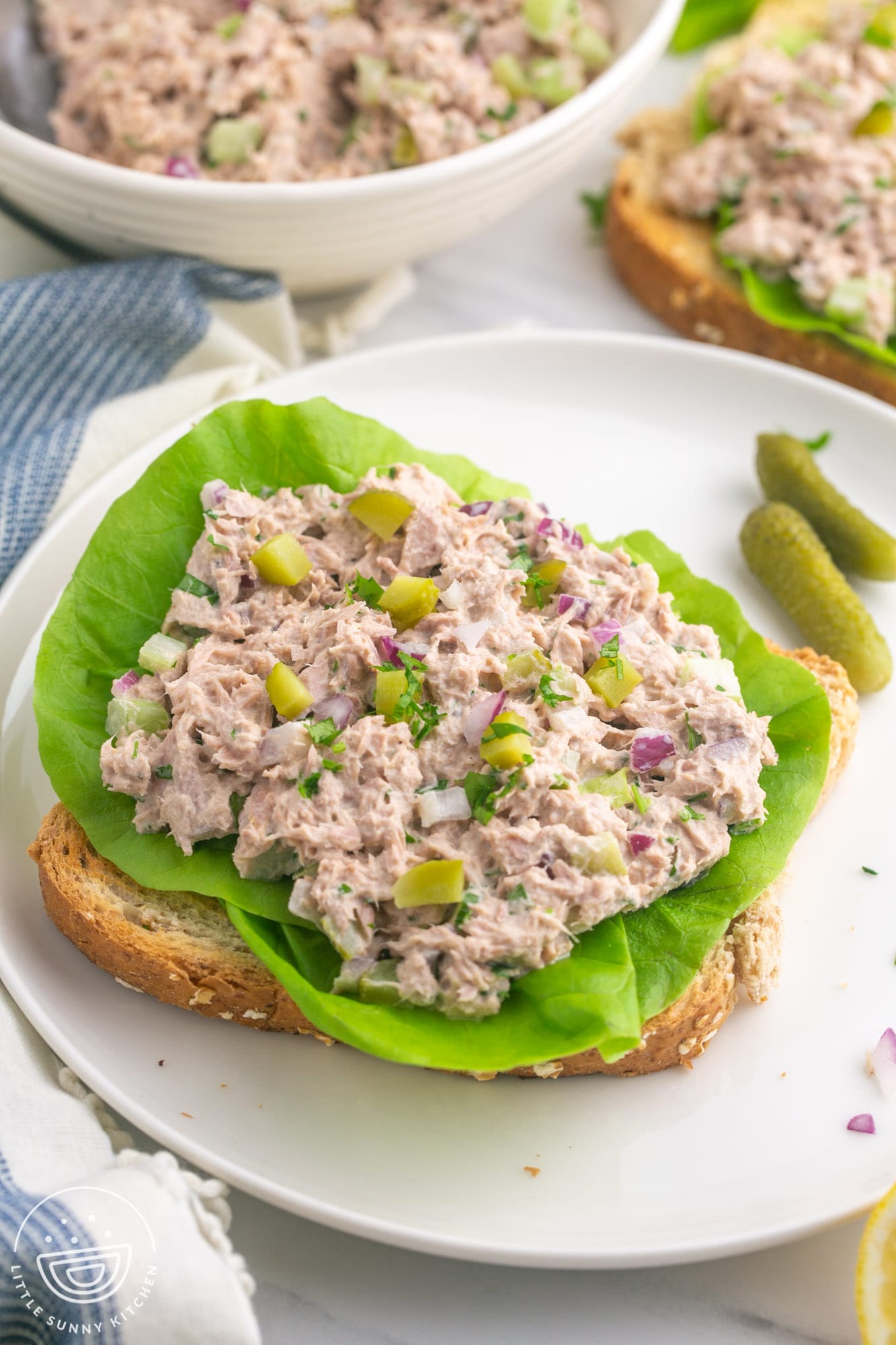 a slice of bread topped with leaf lettuce, topped with fresh tuna salad.