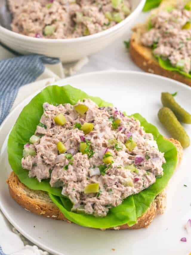 a slice of bread topped with leaf lettuce, topped with fresh tuna salad.