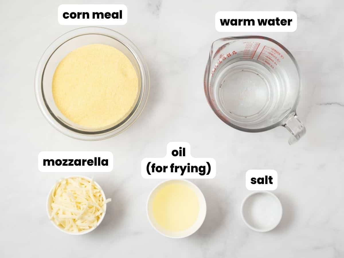 the ingredients needed to make arepas con queso, in small bowls on a counter, viewed from above. 
