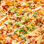 a cast iron skillet filled with buffalo chicken pasta, topped with blue cheese and green onion.