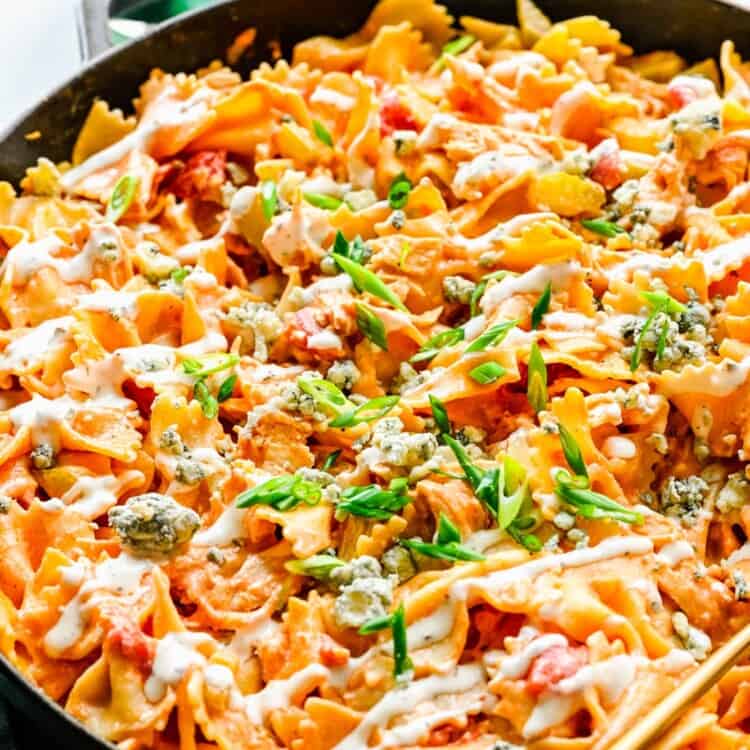 creamy buffalo chicken farfalle pasta being served from a cast iron skillet.