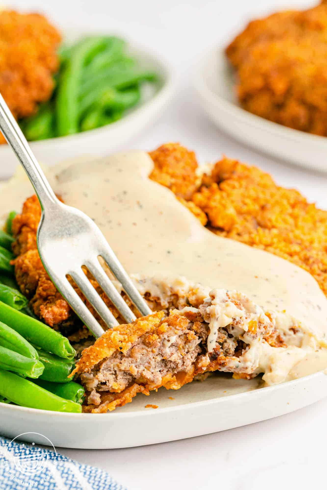 A bite shot of the chicken fried steak, with a fork and some gravy.