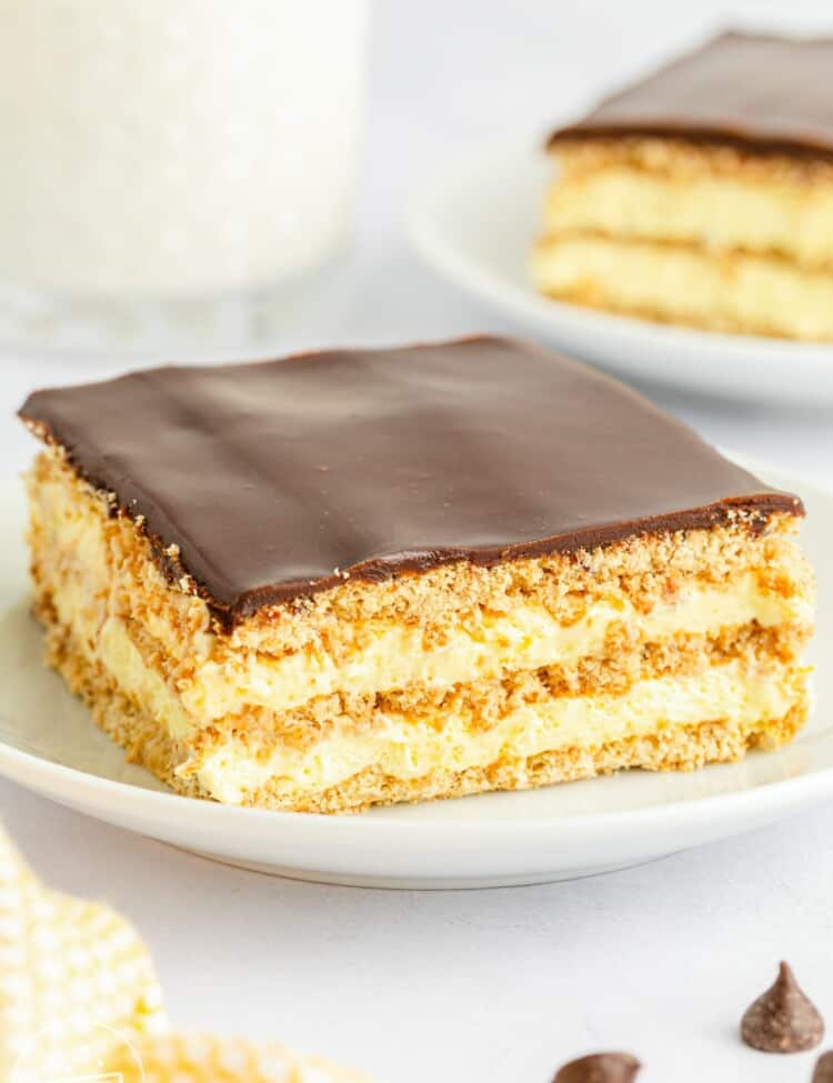 No Bake Eclair Cake slice served on a small white plate, with a glass of milk in the background