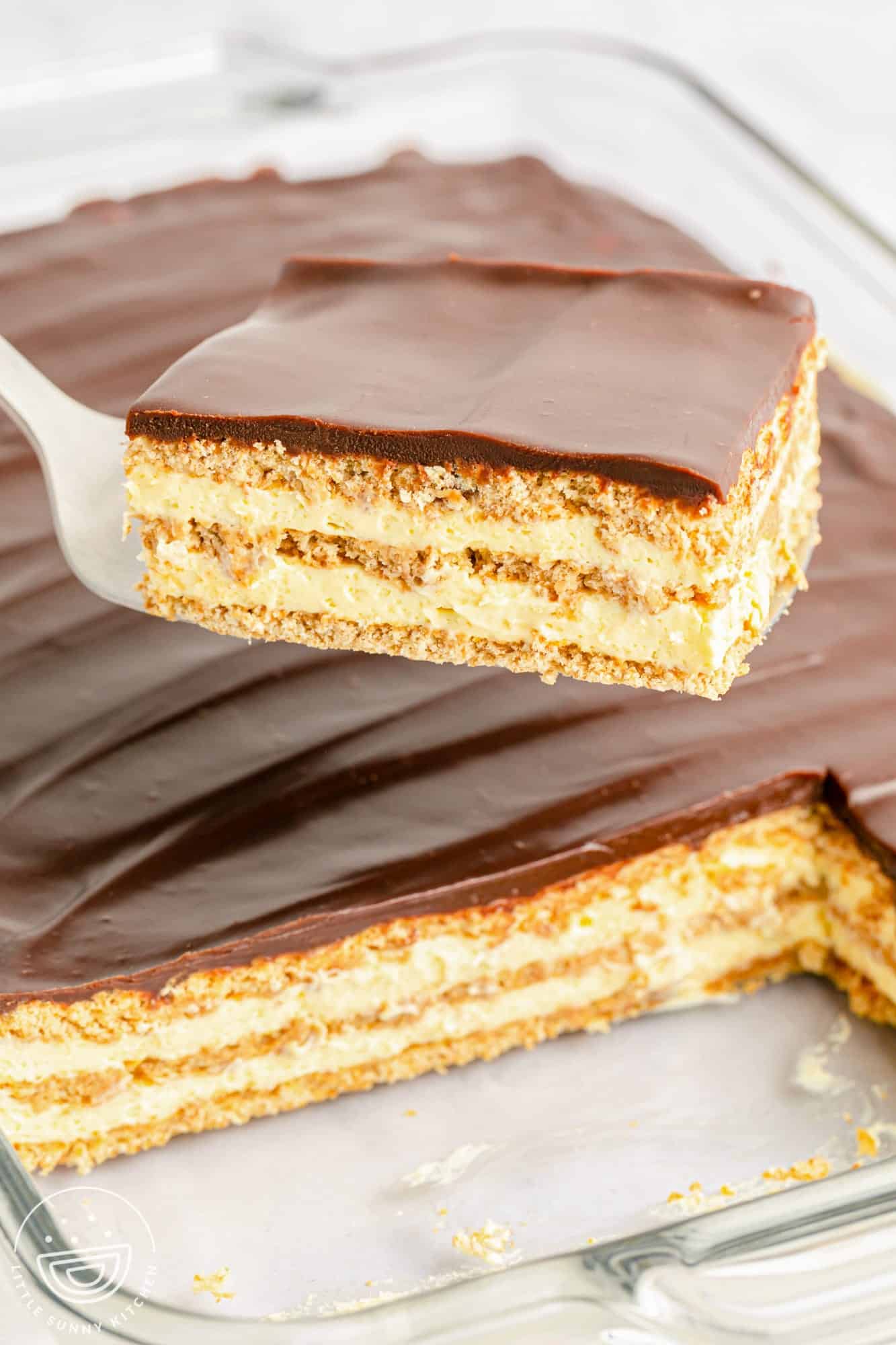 Taking a slice of no bake eclair cake from the pan, using a server