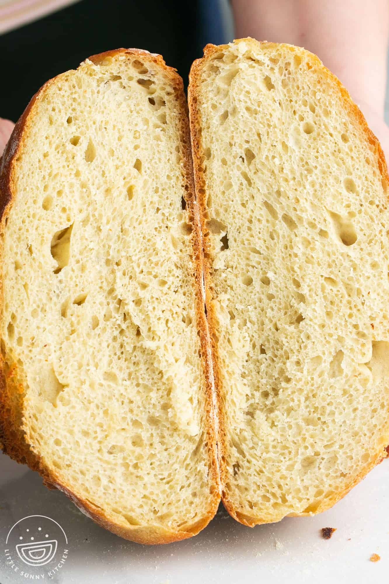 a round loaf of no knead bread, sliced in half to show the crumb.