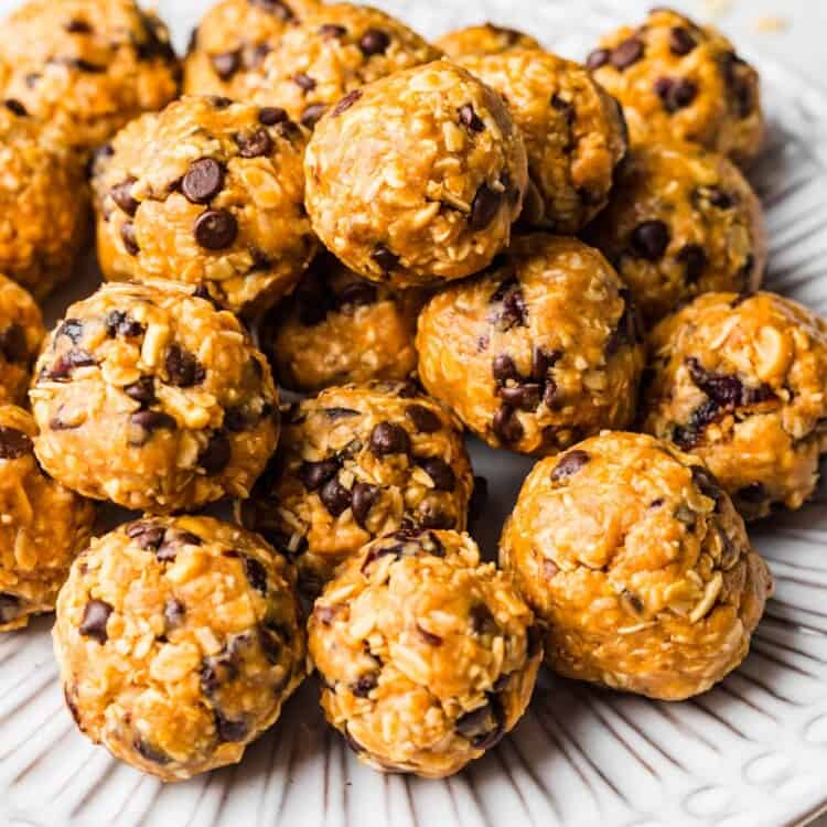 a ridged white plate stacked with chocolate chip oatmeal balls.