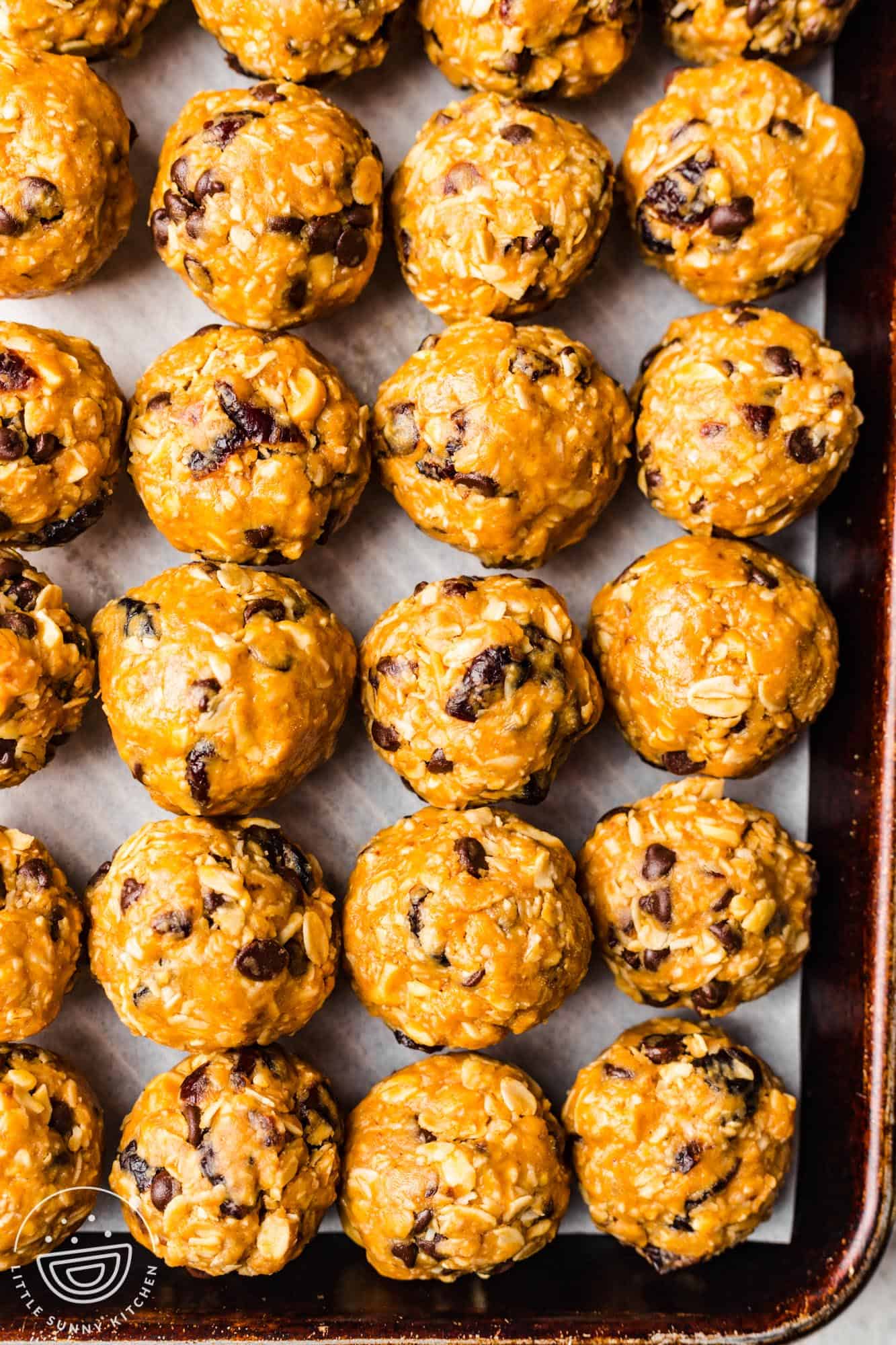 a metal sheet pan with rows of homemade chocolate chip oat bliss balls.