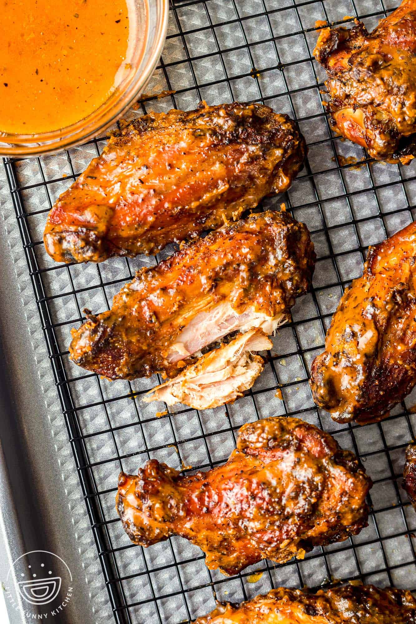 Overhead shot of smoked chicken wings tossed in sauce, and laid on a sheet pan with a wire rack