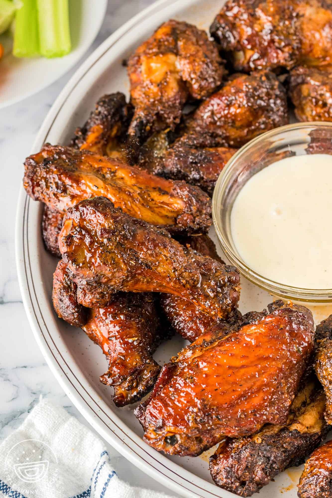 Smoked chicken wings served on a white plate with a small dip with ranch sauce