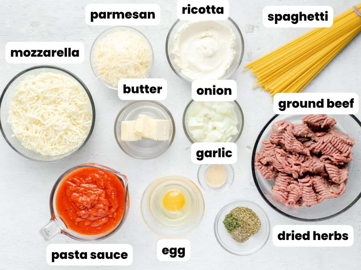 All of the ingredients needed to make spaghetti pie, in small bowls, arranged on a counter and viewed from above.