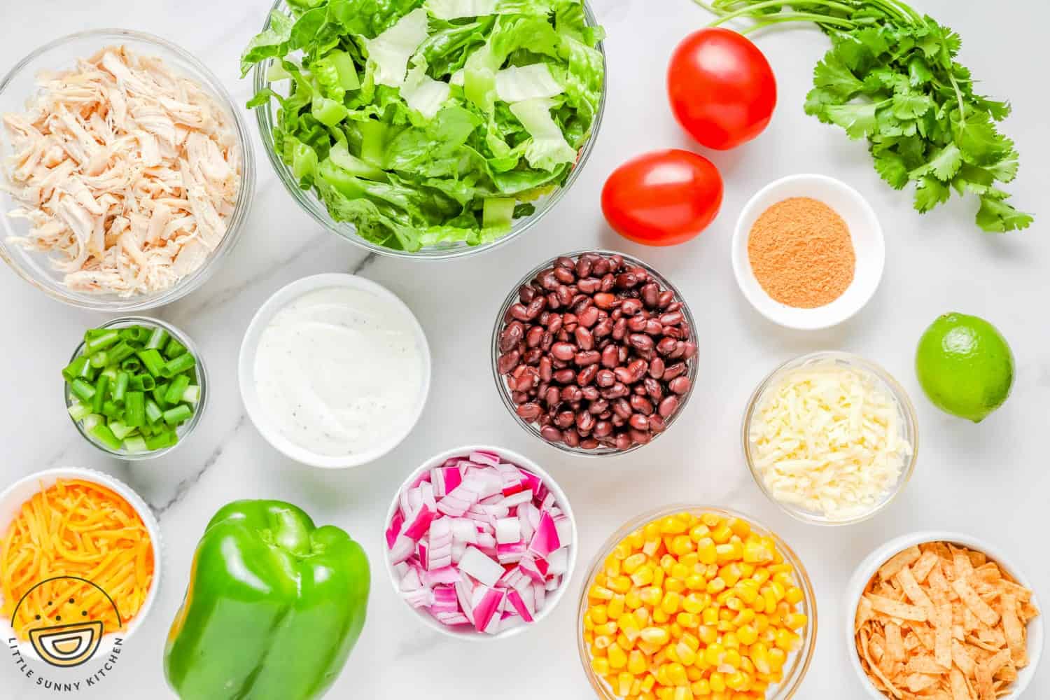 all of the ingredients that go into a tex mex salad, chopped and in small bowls, arranged on a counter.