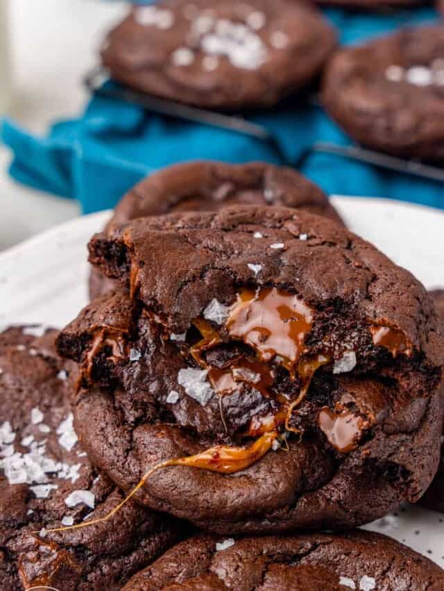 a gooey caramel chocolate cookie on top of a plate of cookies.
