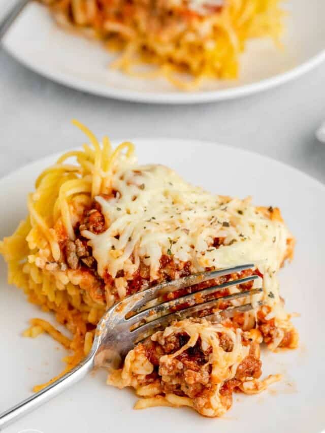 a serving of spaghetti pie on a dinner plate. A fork is picking up a bite.