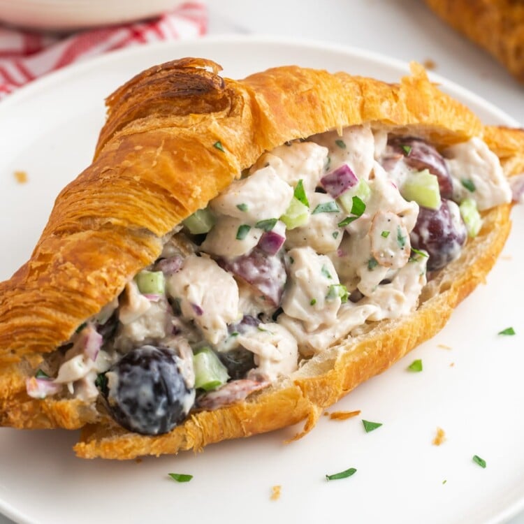 a large croissant cut in half and stuffed with homemade chicken salad with grapes and almonds.