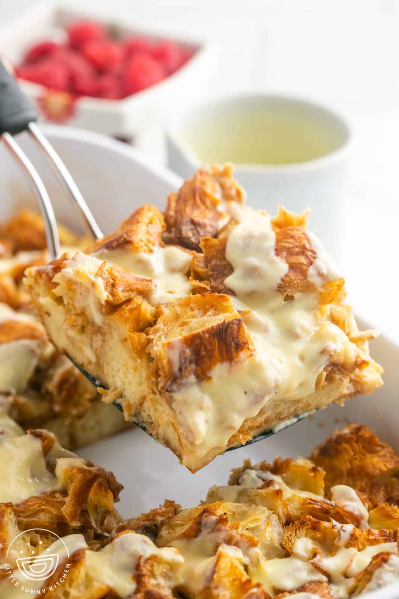 a spatula holding up a square of bread pudding with vanilla sauce.