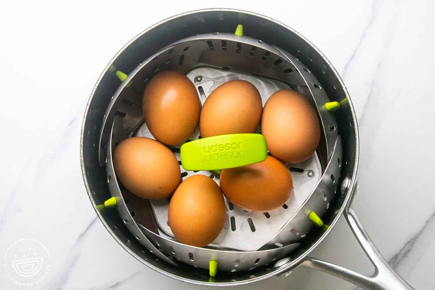 Eggs on a steamer basket in a stainless steel saucepan